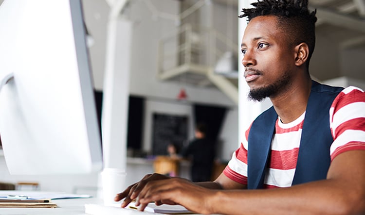 A man sits behind a computer as he works