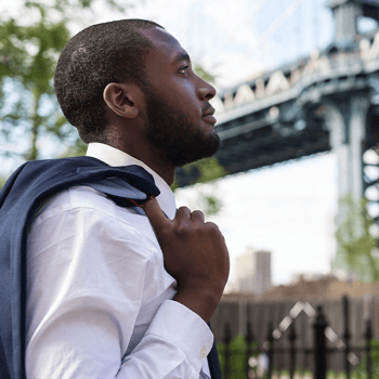 Man with jacket on shoulder looks up at the sky