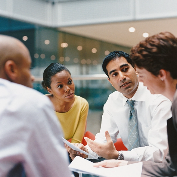 A group of four people sit at a table and discuss