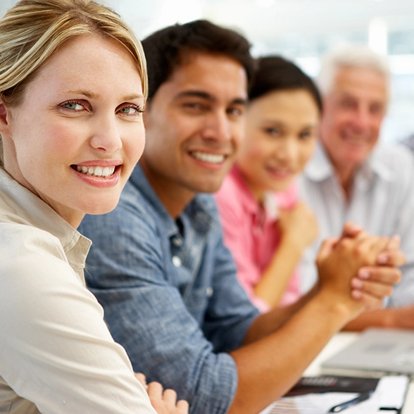 A group of 4 people sit next to each other and smile at the viewer