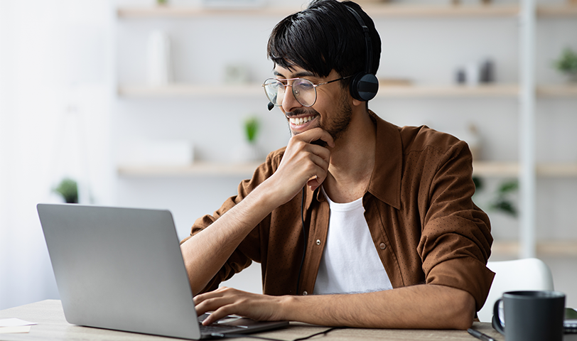 Man with headphones sits at computer and works