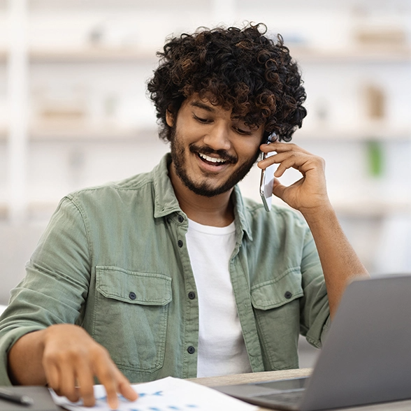 Man talks on the phone while he works on his computer