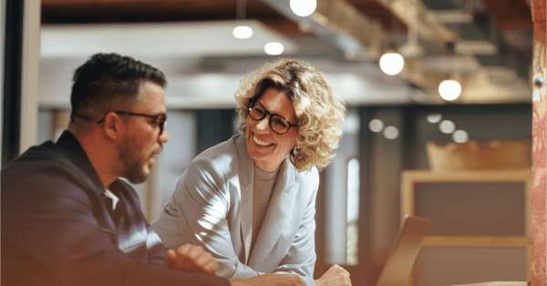 Two business professionals discussing outplacement solutions at a table with a laptop.