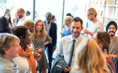 After reading a blog on how to network for a job, a diverse group of smiling professionals attends a local networking event, engaging in meaningful conversations and building connections with others who share similar career interests. 