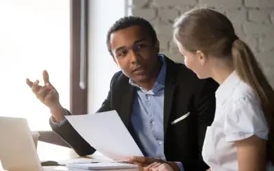 After a RIF, a coach and employee review next career steps together during an outplacement session with a laptop open.
