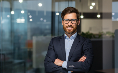 A confident, approachable leader in a suit smiles with arms crossed. His recent promotion is the result of a research-backed leader assessment.