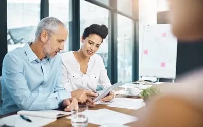 A coach and coachee meet at a conference table, reflecting the company’s executive coaching programs. 