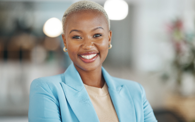 A confident female leader in a business suit smiles in a modern office, representing how leadership assessments help women in leadership roles by bridging the gender gap and reducing bias in the hiring and selection process.