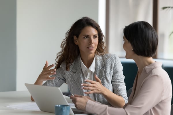 Un accompagnateur de carrière et un participant, tous deux vêtus de façon professionnelle, sont assis à une table de conférence, un ordinateur portable ouvert entre eux, et participent activement à une séance individuelle de coaching dans le cadre d’un programme de replacement externe.